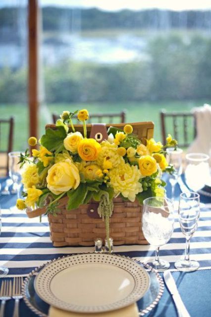 a basket box with yellow ranunculus and garden roses, billy balls and dahlias and some leaves for a bold wedding