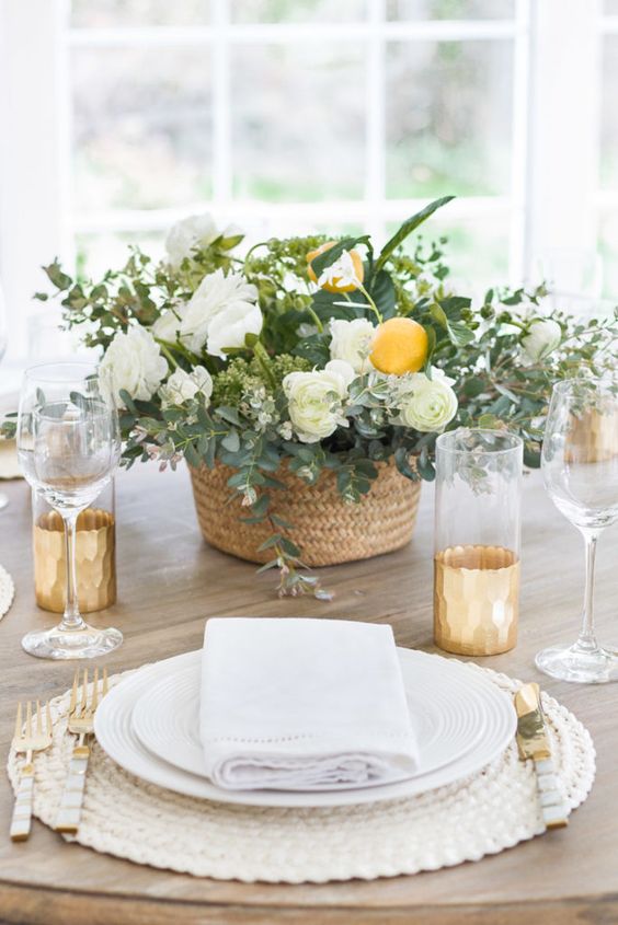 a basket wedding centerpiece of white ranunculus, greenery and lemons is a cool idea for a spring or summer wedding