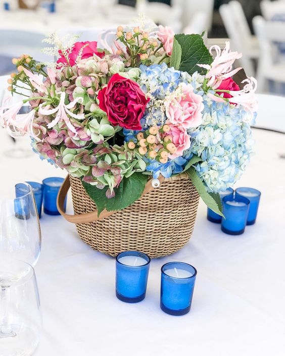 a basket with burgundy peonies, blue and green hydrangeas, pink roses and berries and greenery is a cool idea for spring or summer