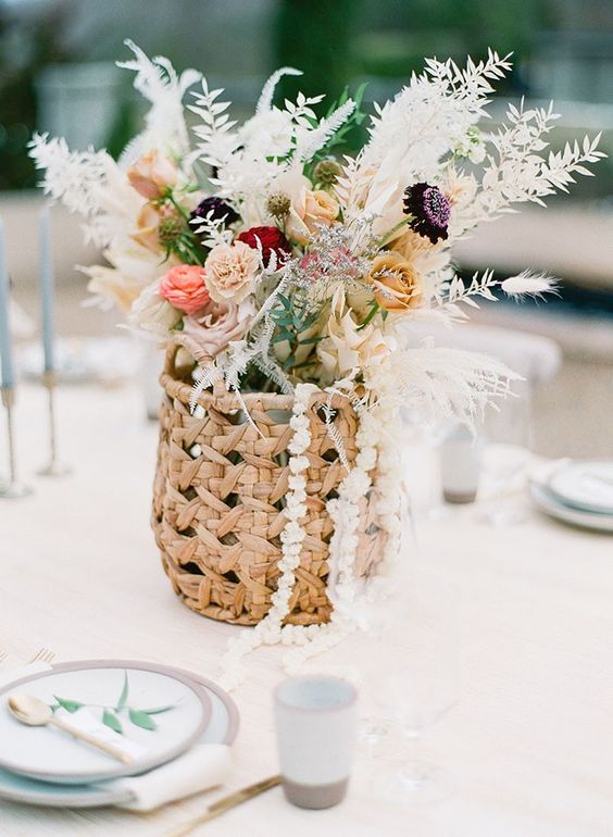 a basket with roses and garden roses, dried leaves and grasses is a cool idea for a boho wedding, it looks creative