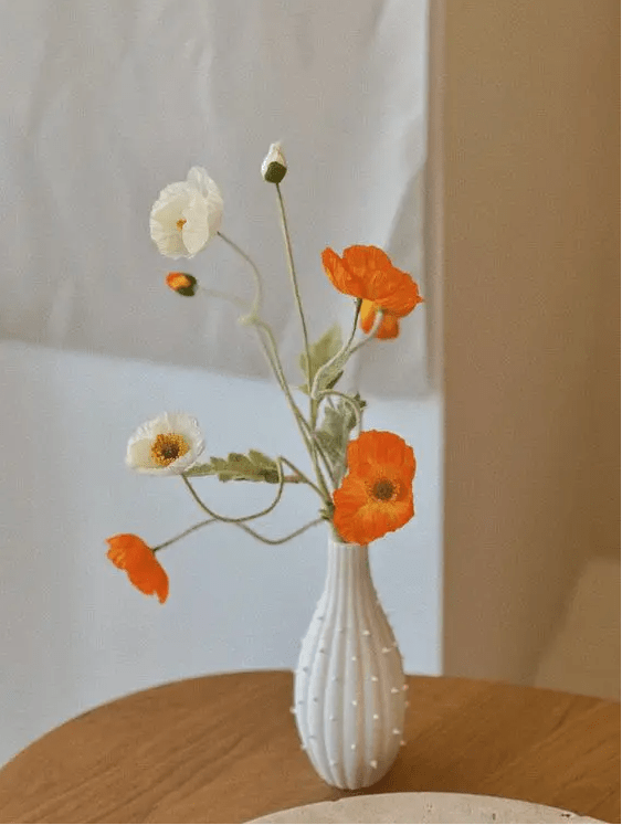 a beauitful and delicate wedding centerpiece of a white polka dot vase, white and orange poppies is a great idea for spring or summer