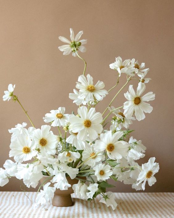 a beautiful and airy white wedding centerpiece of sweet peas and cosmos is adorable for a modern wedding