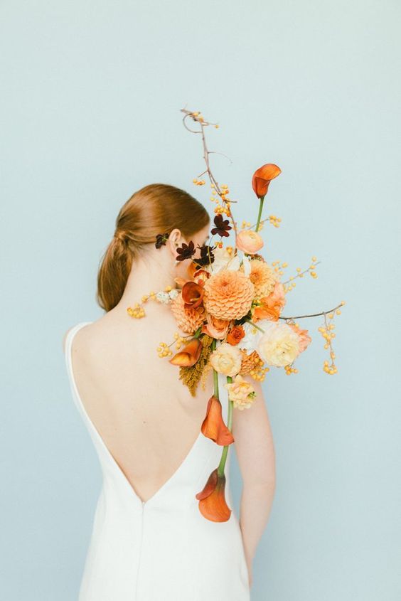 a beautiful fall wedding bouquet of orange callas, mums, berries, twigs and some dark mini blooms