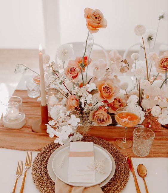 a beautiful orange and white wedding centerpiece of white orchids, orange roses, white mums and other fillers for a fall boho wedding