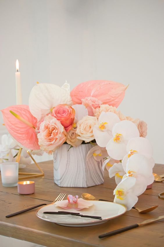 a beautiful pink wedding centerpiece of blush, neutral and pink roses, white orchids and white and pink anthuriums