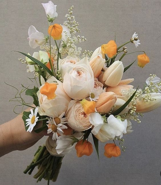 a beautiful spring wedding bouquet with chamomiles, peonies, blush and white tulips, sweet peas, greenery and yellow touches