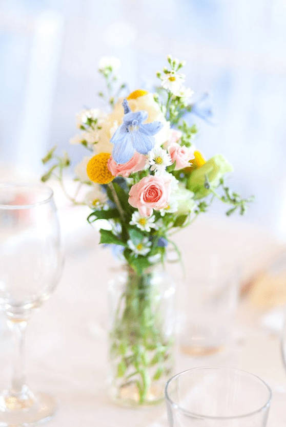 a beautiful summer wedding centerpiece of greenery, blue and pink blooms and billy balls is a lovely idea for a brigth wedding