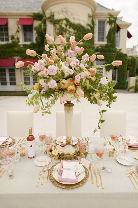 a beautiful tall vintage wedding centerpiece of pink and light yellow and peachy blooms including roses and tulips
