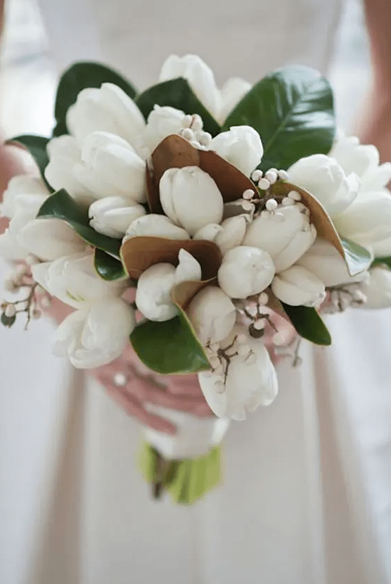 a beautiful wedding bouquet of white tulips, magnolia leaves and berries is a lovely idea for a spring or summer wedding