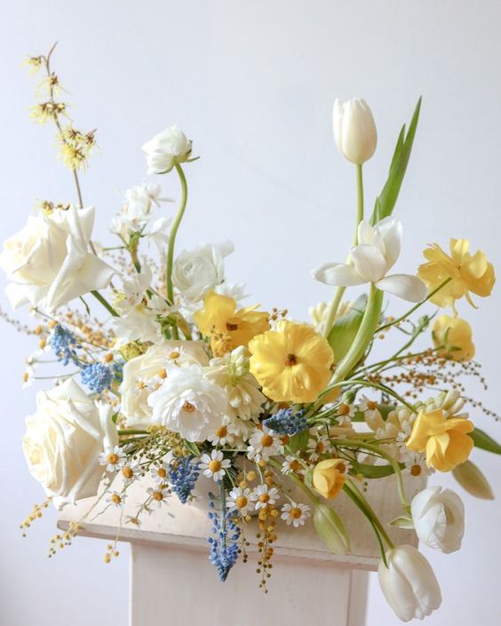 a beautiful wedding centerpiece of white roses, tulips, yellow rulips and poppies, chamomiles and blue touches