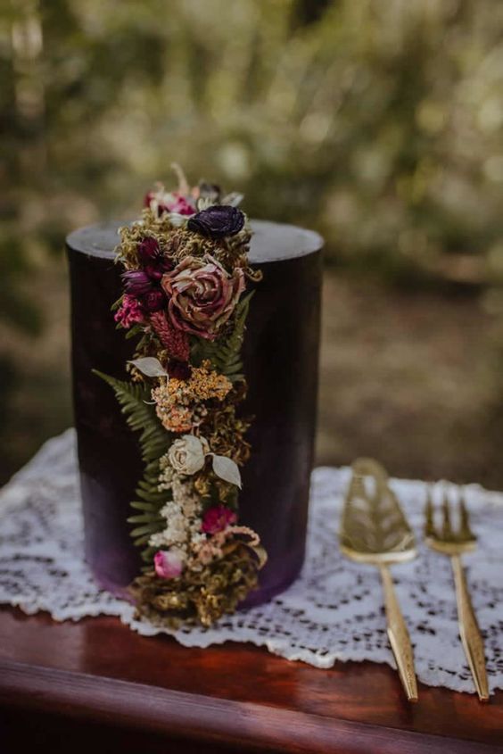 a black wedding cake decorated with moss, fern and bright blooms is a cool decadent idea for the fall