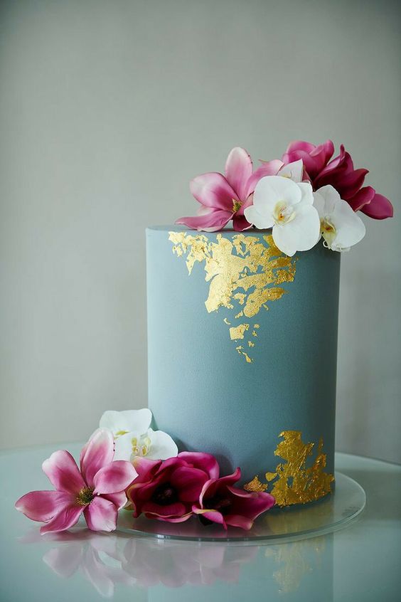a blue tall wedding cake with gold leaf and fuchsia and white blooms is a stunning idea for a colorful wedding