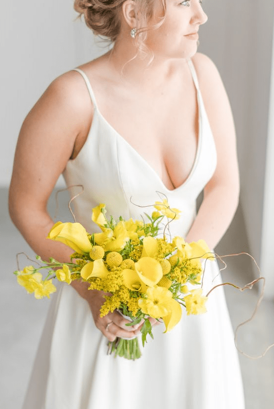 a bold wedding bouquet of yellow callas, mimosa, billy balls and some greenery and twigs is a very bold and cool idea