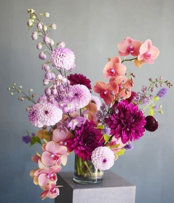 a bold wedding centerpiece of pink and orange orchids, pink mums, purple dahlias and some colorful fillers is wow