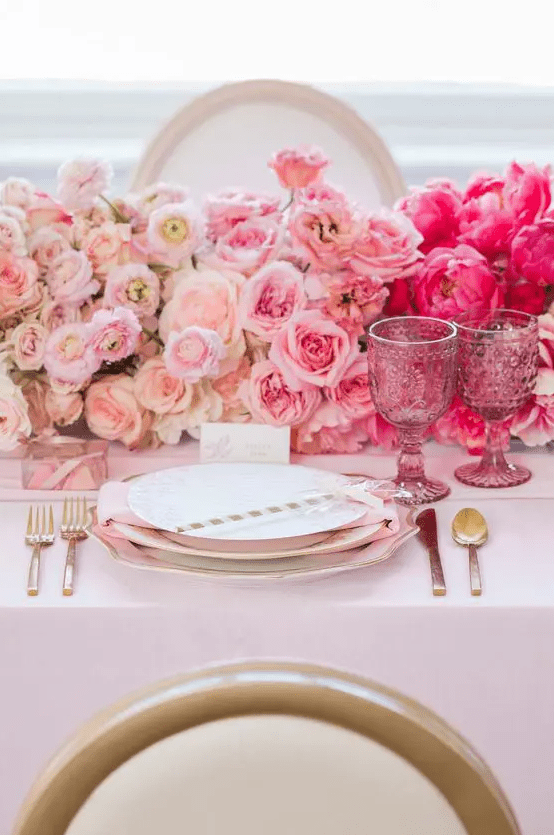 a bright ombre Valentine's Day wedding table with blush to fuchsia floral runner, gold rimmed plates and gold cutlery and pink glasses