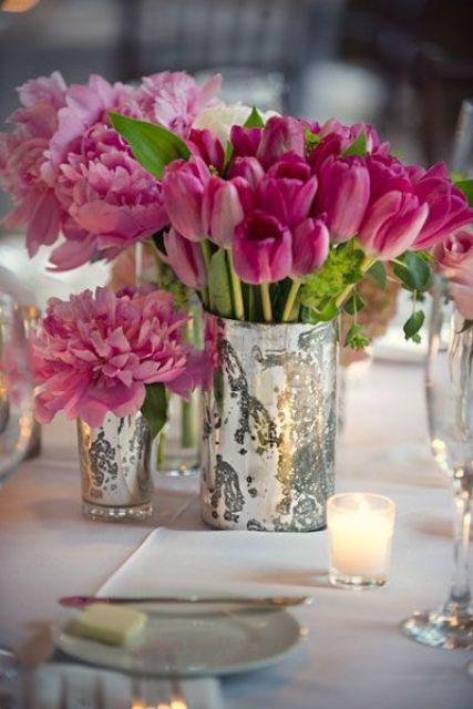 a bright pink wedding centerpiece of peonies and tulips in mercury glass vases for a fun and playful feel at the wedding