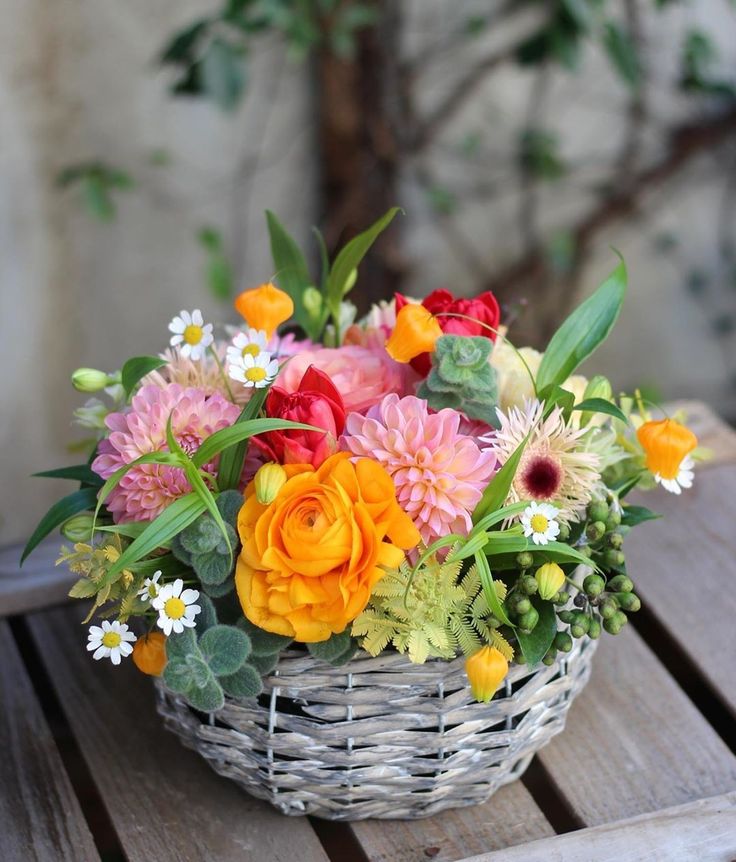 a bright summer wedding centerpiece of a basket with greenery, berries, pink, yellow and red blooms is wow