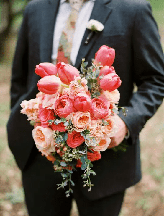 a bright wedding bouquet of bold pink tulips and peachy peony roses plus some greenery and berries is a cool idea for a bright wedding
