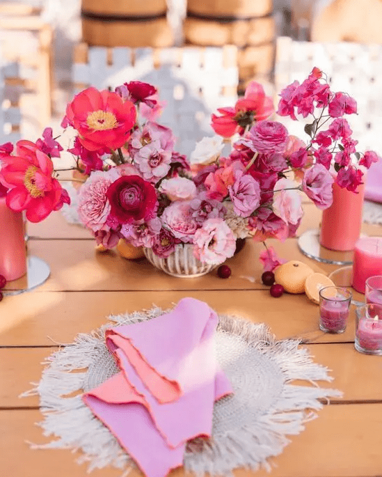 a bright wedding centerpiece of blush, light pink and fuchsia blooms including carnations for a colorful wedding