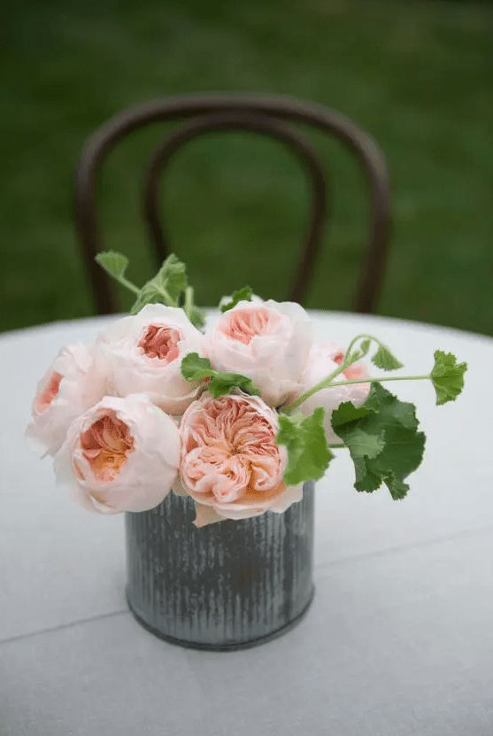 a chic and easy wedding centerpiece of blush peonies and greenery in a metal vase is a stylish solution for summer