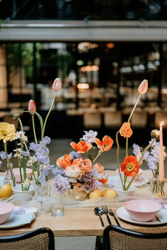 a colorful artful wedding centerpiece of various blooms in pastel and bright colors including tulips, daffodils and others