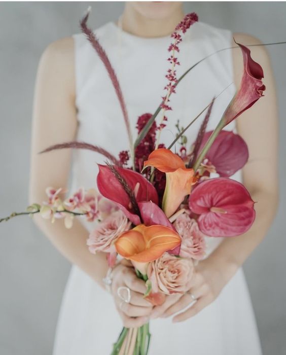 a colorful wedding bouquet of peachy and purple callas, anthuriums, roses and some fillers for a fall wedding