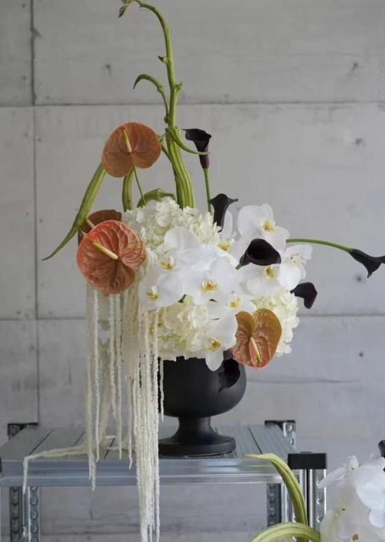 a creative modern wedding centerpiece of white hydrangeas and orchids, anthuriums, deep purple callas and amaranthus
