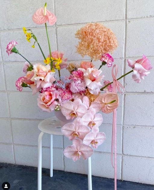 a creative wedding centerpiece of blush orchids, pink and blush roses and carnations, anthuriums and hydrangeas
