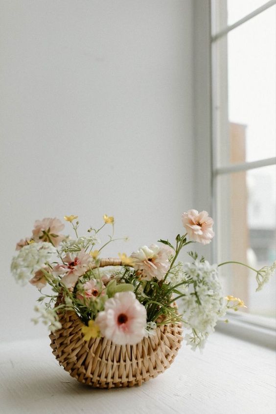a cute spring wedding centerpiece of a basket with white, blush and yellow blooms can be easily DIYed