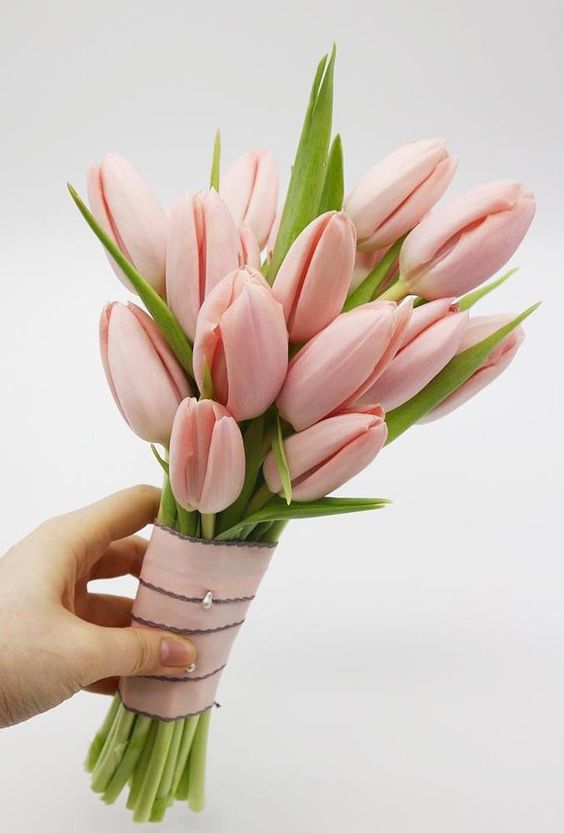a delicate small pink tulip wedding bouquet with some leaves is a chic and lovely solution for spring, it looks awesome