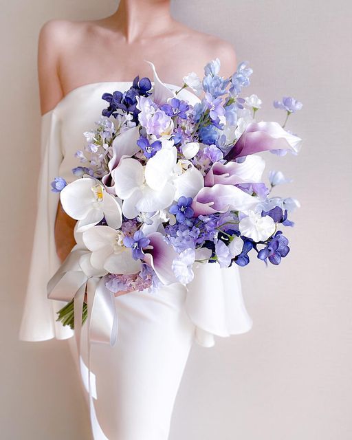 a fantastic spring wedding bouquet of white orchids and sweet peas, lilac callas, purple orchids and delphinium