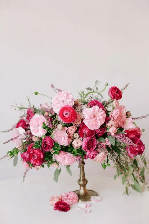 a gorgeous lush Valentine's Day wedding centerpiece of fuchsia, light pink and blush blooms and greenery is adorable