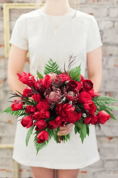 a gorgeous red and burgundy blooms and ferns and greenery is a beautiful statement with color for a Valentine bride