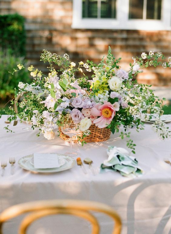 a gorgeous spring or summer wedding centerpiece of a basket, lilac and pink roses, lots of greenery and blooming branches is wow