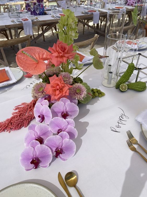 a gorgeous tropical wedding centerpiece of coral roses, anthurium, pink orchids and amaranthus, dahlias and green hydrangeas