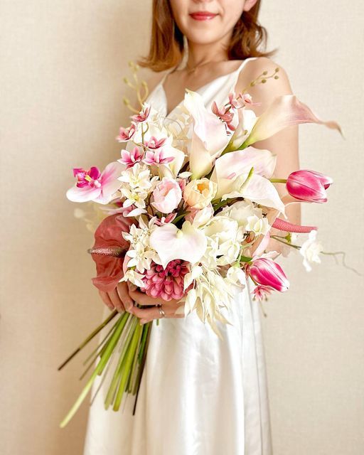 a gorgeous wedding bouquet of pink and blush tulips, pink orchids and blooming branches, some white fillers and blush callas