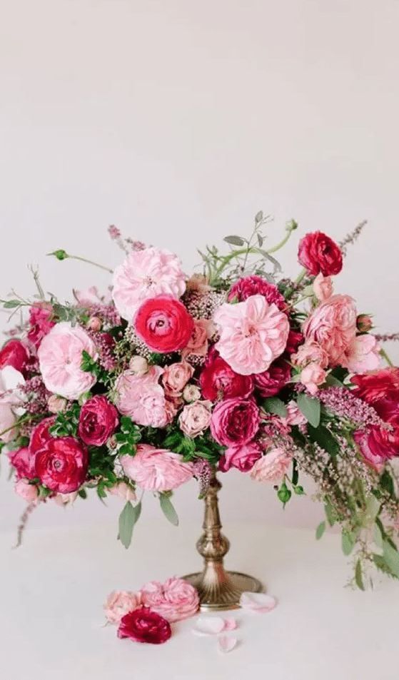 a gorgeous wedding centerpiece of pink peonies, fuchsia peony roses, pink ranunculus and greenery and astilbe is fantastic for a Valentine’s Day wedding