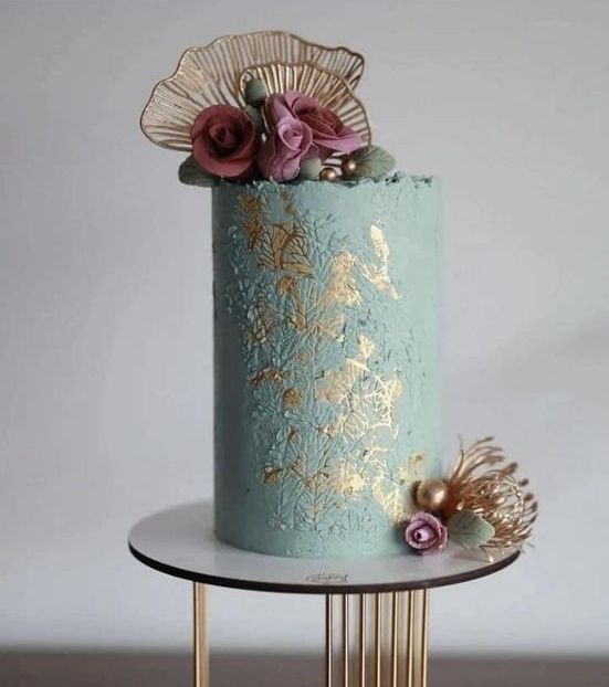 a green textural tall wedding cake with gold touches, fuchsia blooms and gold touches is very elegant