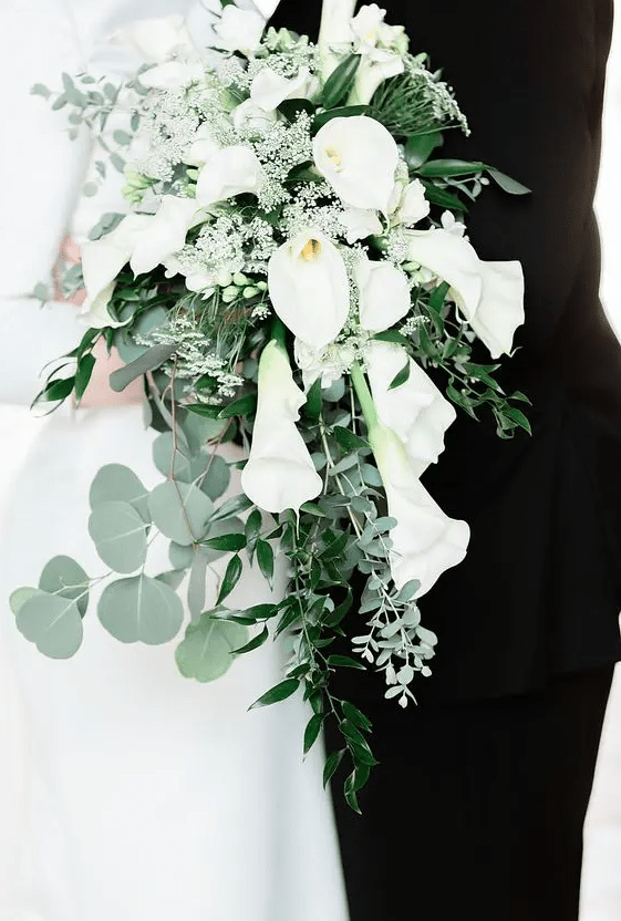 a lovely cascading wedding bouquet of white calla lilies, small white fillers and several kinds of greenery