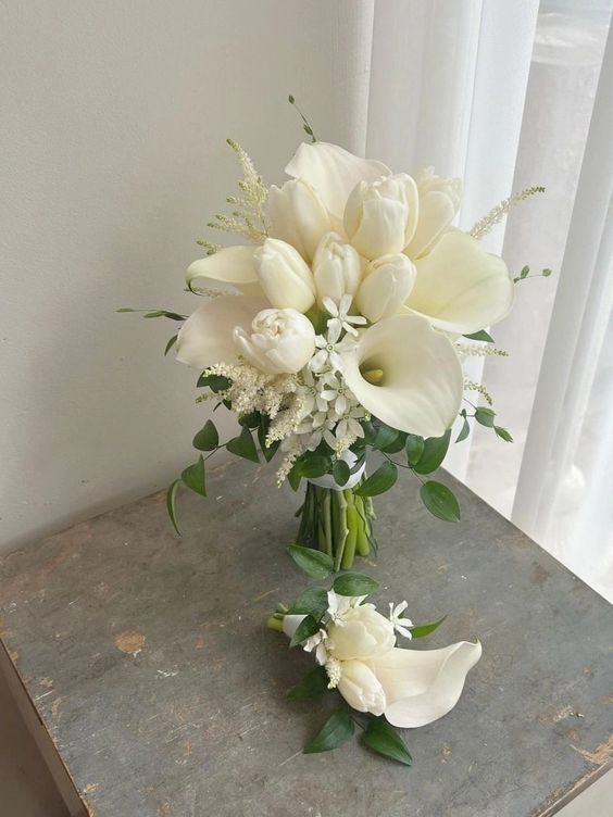 a lovely modern white wedding bouquet of callas, ulips, some fillers and greenery for a spring or summer wedding
