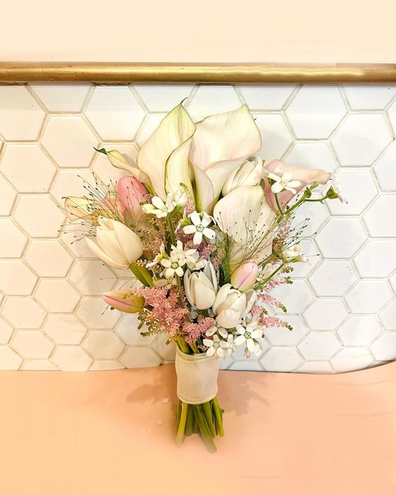 a lovely neutral wedding bouquet of white callas, tulips, pink tulips and callas, small pink and white fillers