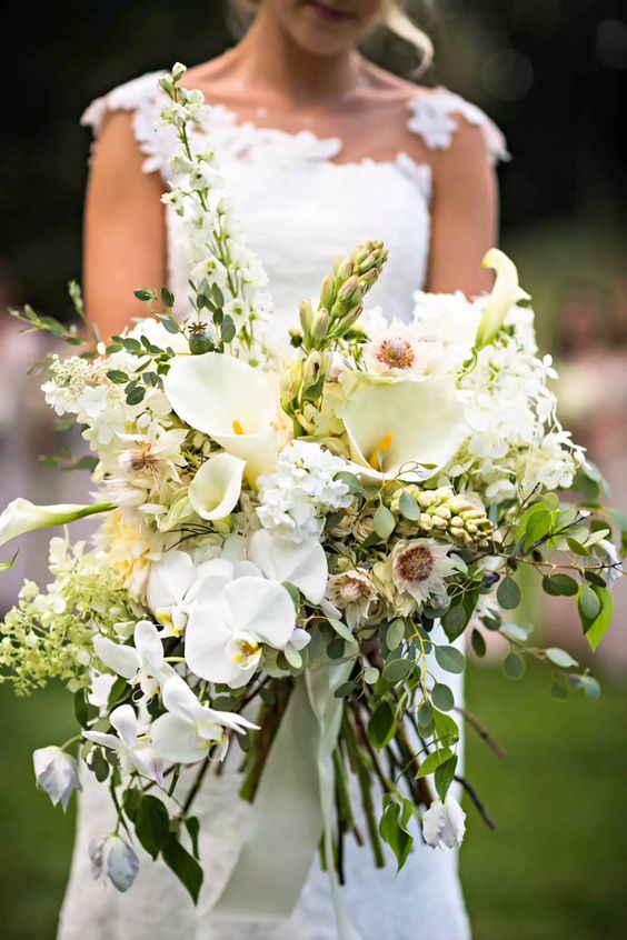 a lush spring wedding bouquet of white callas and orchids, greenery, some fillers and green hydrangeas