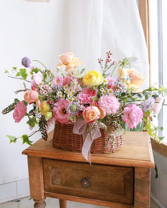 a lush summer wedding centerpiece of a basket, pink, yellow and lilac blooms and greenery is fantastic