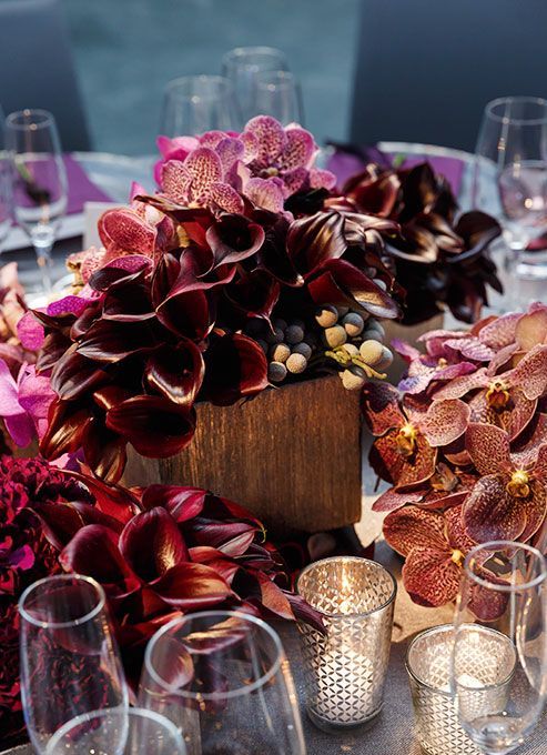 a lush wedding centerpiece of deep purple callas, pink orchids and berries cascadign down to the table for a moody wedding