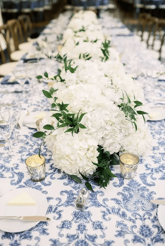 a lush white hydrangea wedding table runner with greenery and candles is a cool idea for a rustic wedding