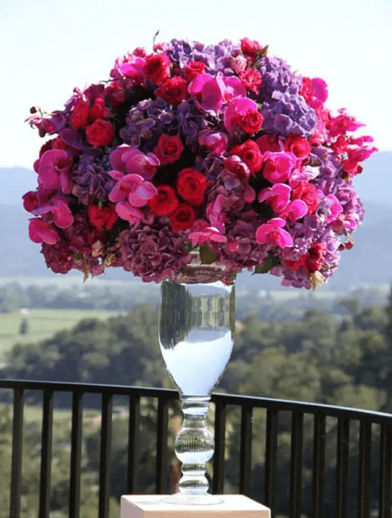 A luxurious tall wedding centerpiece done in jewel tones, with hot pink, deep red and violet blooms is a jaw dropping idea