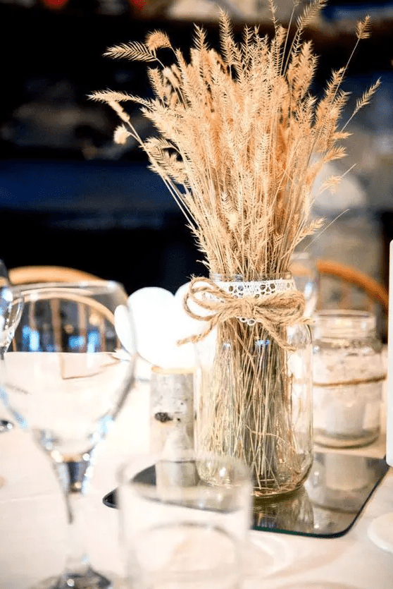 a mason jar with twine and wheat looks rustic and cute, and a mirror underneath gives it a fresh modern feel