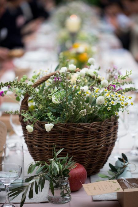 a messy basket wedding centerpiece of greenery and some wildflowers is amazing for a woodland or rustic wedding