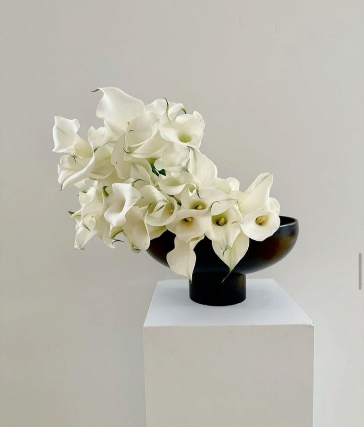 a modern and creatively shaped wedding centerpiece of a black bowl with white callas is a lovely and catchy idea