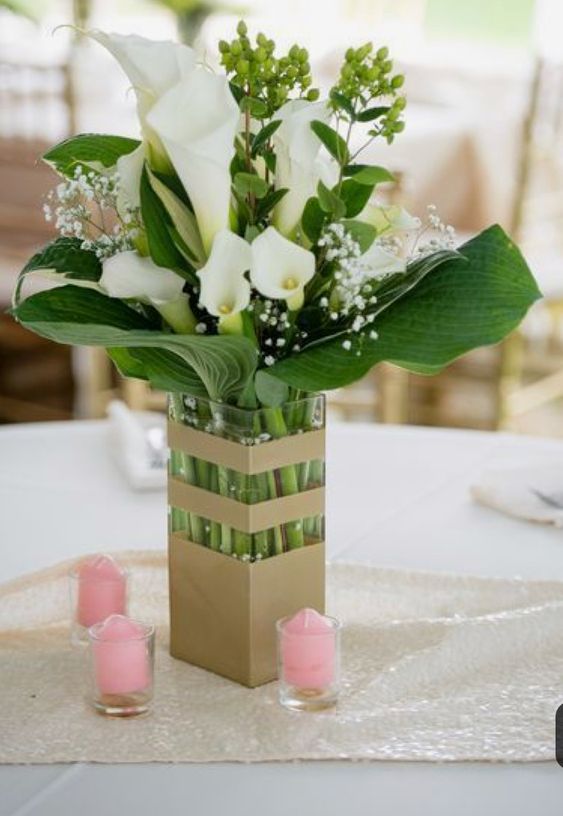 a modern wedding centerpiece of a gold striped vase, leaves, white callas, berries and fillers is a cool and catchy idea to rock